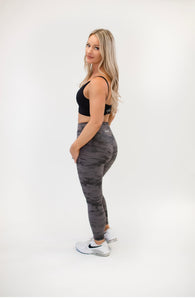 Picture of a female model with blonde hair wearing grey Napa Leggings from Roach Co, a black sports bra and white tennis shoes.